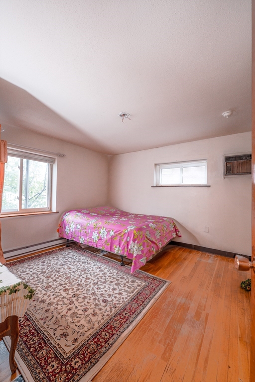 851 Broadway, Unit 21 Everett, MA 02149 - Photo 7 of 10 a bedroom with a bed and wooden floor