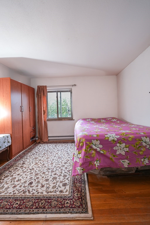 851 Broadway, Unit 21 Everett, MA 02149 - Photo 8 of 10 a bedroom with a bed and wooden floor