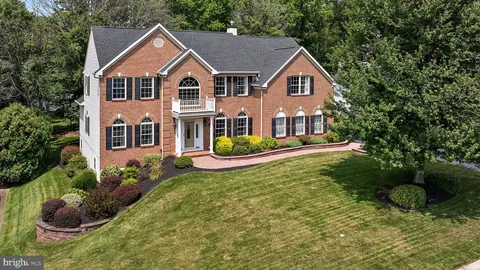 a front view of a house with garden and trees