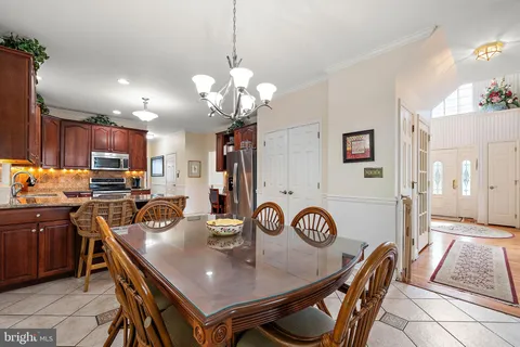 a kitchen with stainless steel appliances a sink a stove a refrigerator cabinets and a dining table