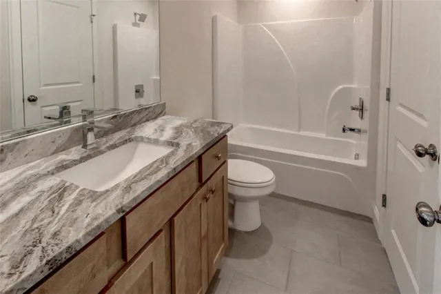 a bathroom with a granite countertop sink a toilet and bathtub