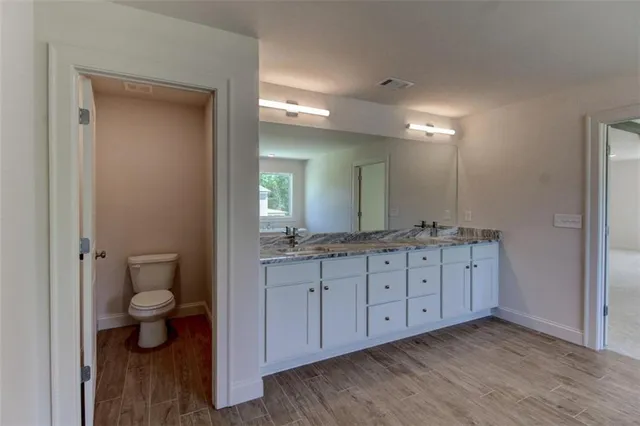 a bathroom with a granite countertop sink a toilet and a large mirror