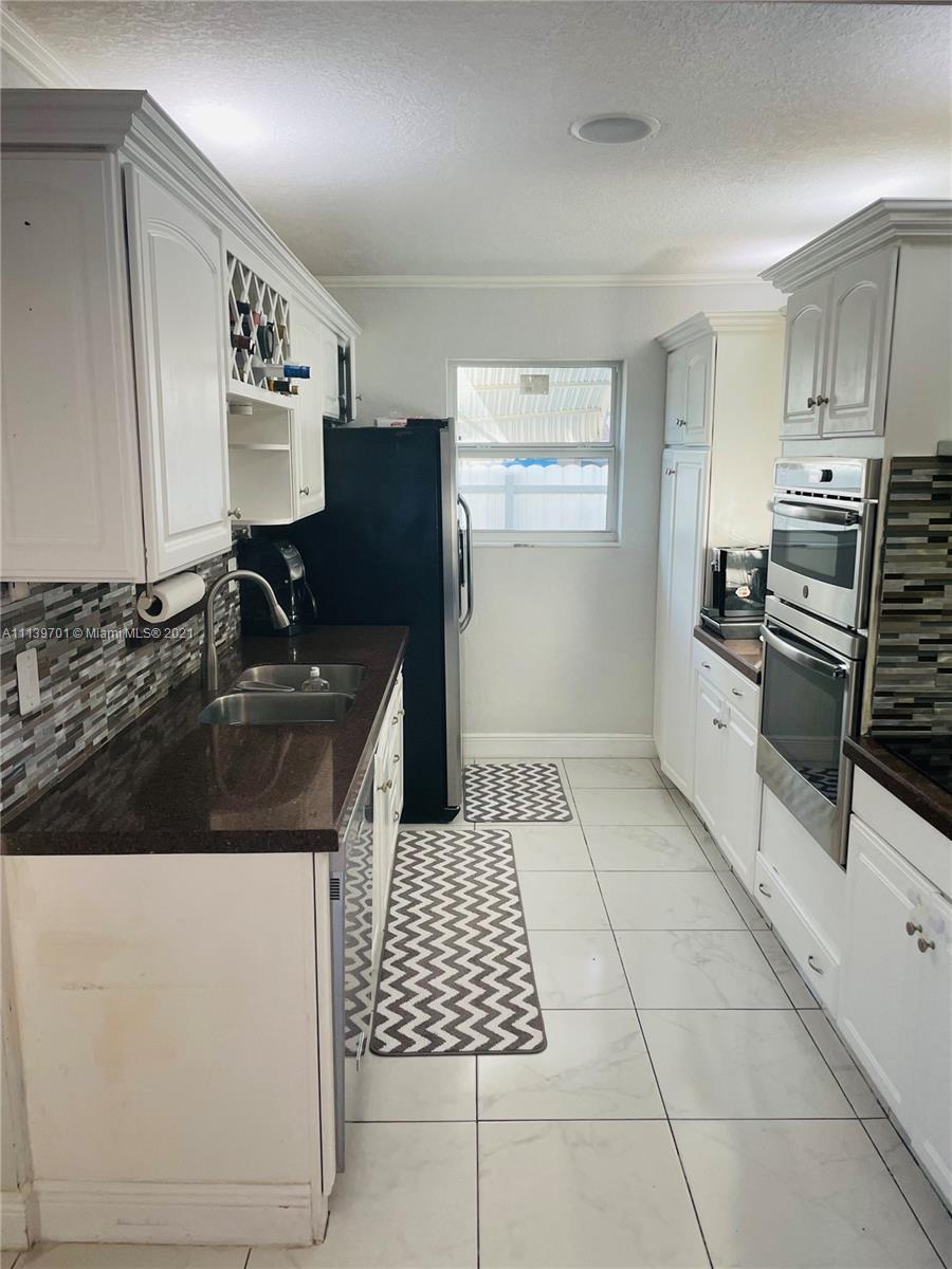 211 Southeast 3rd Street Dania Beach, FL 33004 - Photo 7 of 21 a kitchen with granite countertop a sink a stove a refrigerator and cabinets
