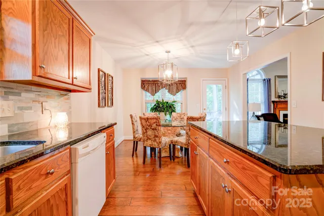 a dining hall with stainless steel appliances granite countertop a stove and a view of living room