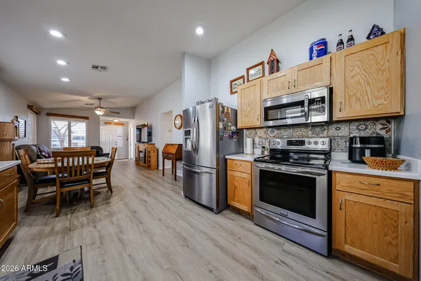 a kitchen with stainless steel appliances granite countertop a stove top oven a refrigerator a dining table and chairs with wooden floor