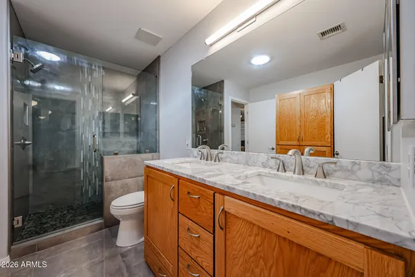 a bathroom with a granite countertop toilet sink and mirror