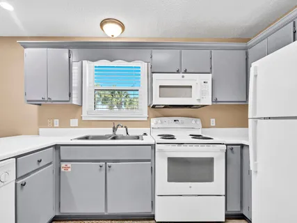 a kitchen with cabinets appliances a sink and a window