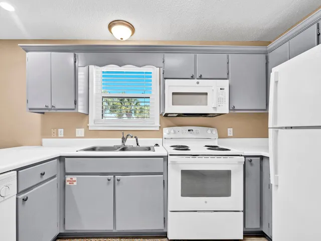 a kitchen with cabinets appliances a sink and a window