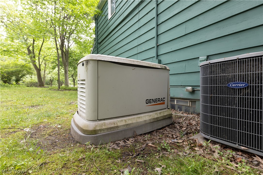25001 Letchworth Road Beachwood, OH 44122 - Photo 49 of 50 Generac home standby generator and Carrier outdoor HVAC unit situated alongside a residential structure with green siding