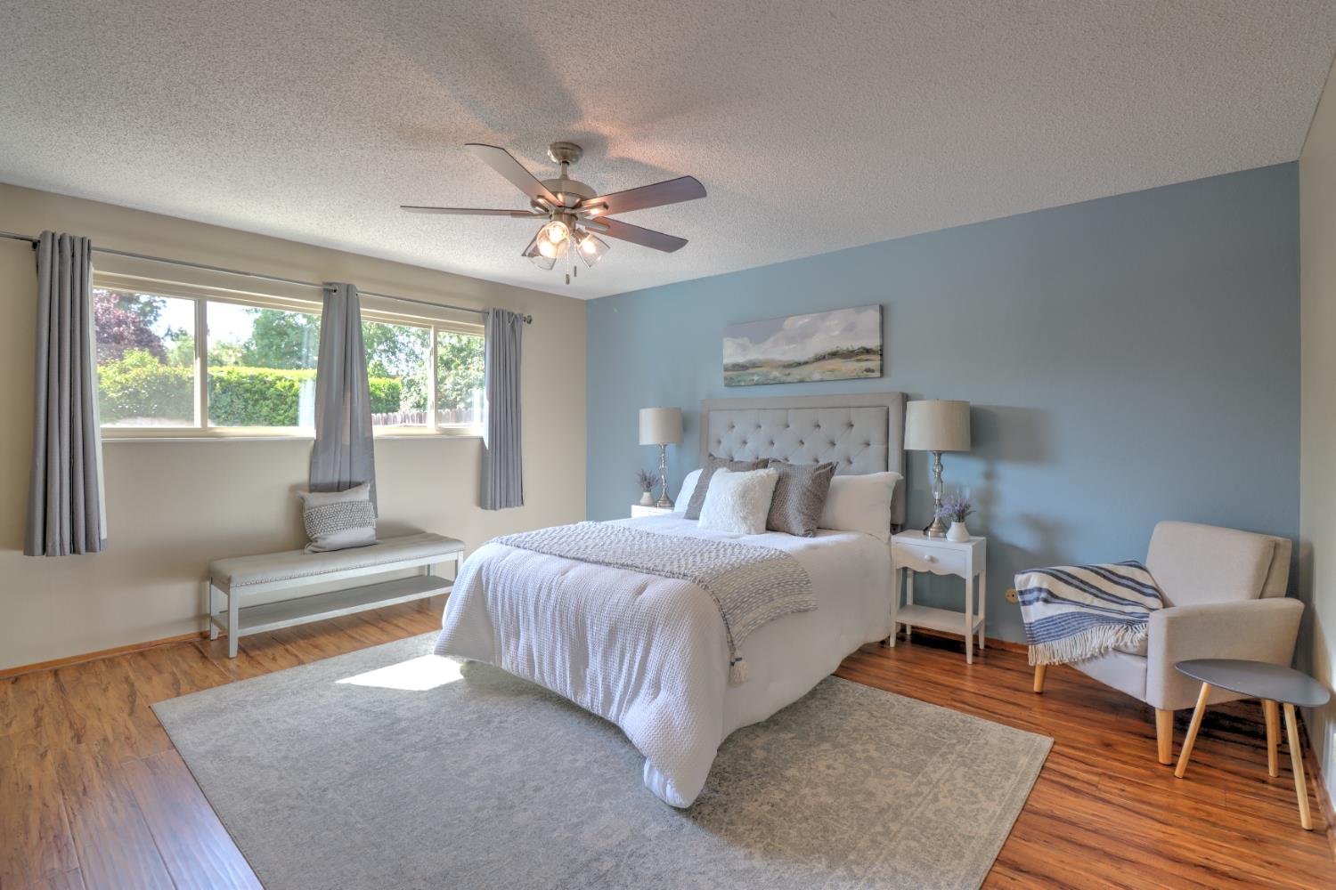 6265 North Colonial Avenue Fresno, CA 93704 - Photo 15 of 22 a bedroom with a large bed a chandelier and windows