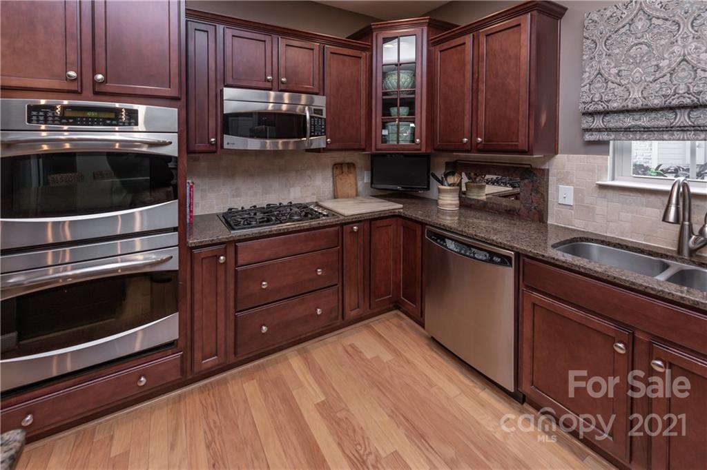 4825 Polo Gate Boulevard Charlotte, NC 28216 - Photo 5 of 30 a kitchen with stainless steel appliances granite countertop wooden cabinets and a stove top oven
