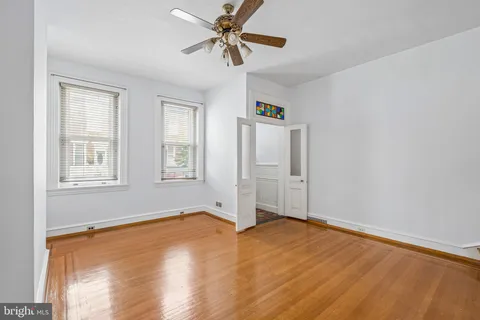 a view of empty room with wooden floor and fan