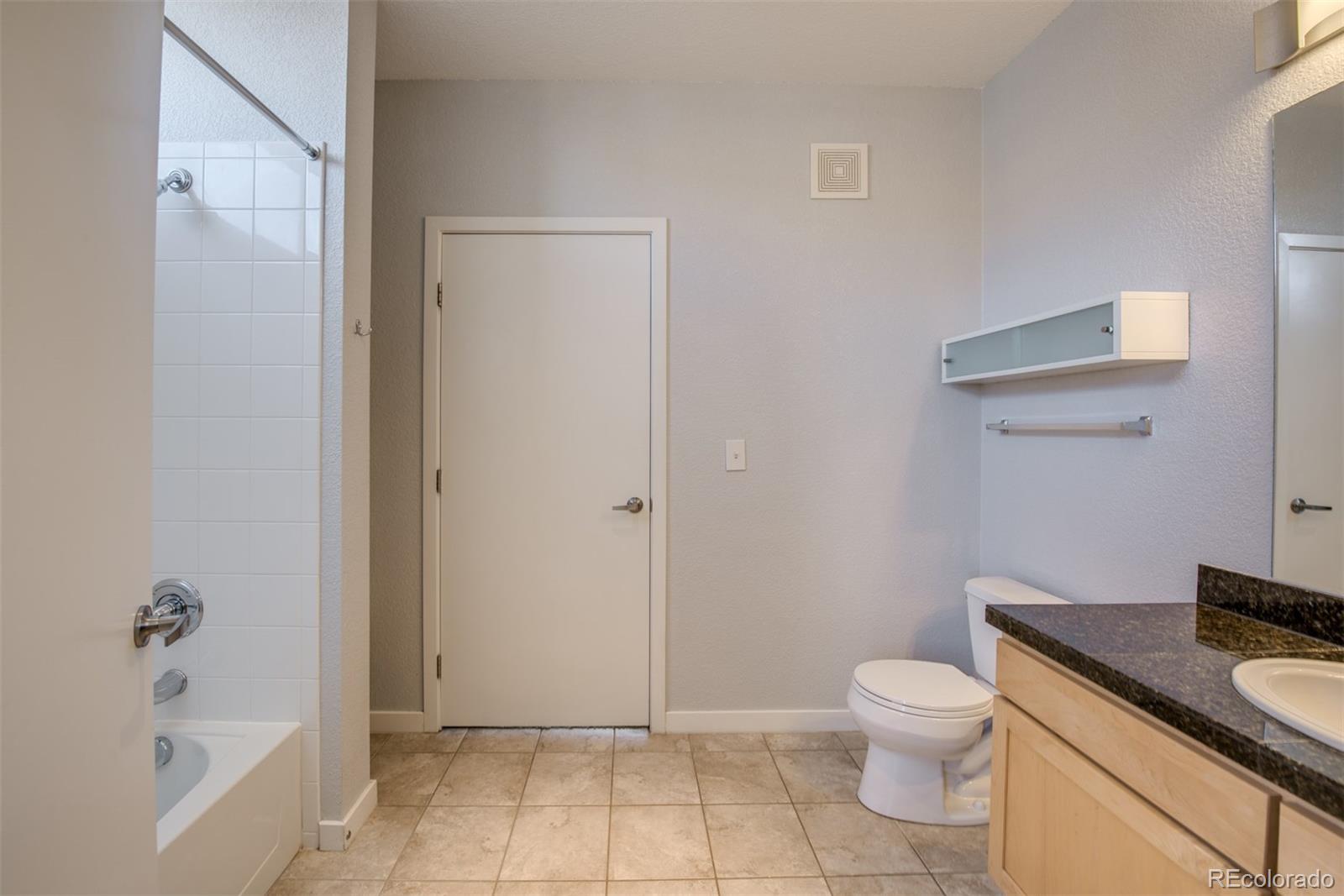 3101 Blake Street, Unit 308 Denver, CO 80205 - Photo 12 of 30 a bathroom with a granite countertop sink a toilet and bathtub