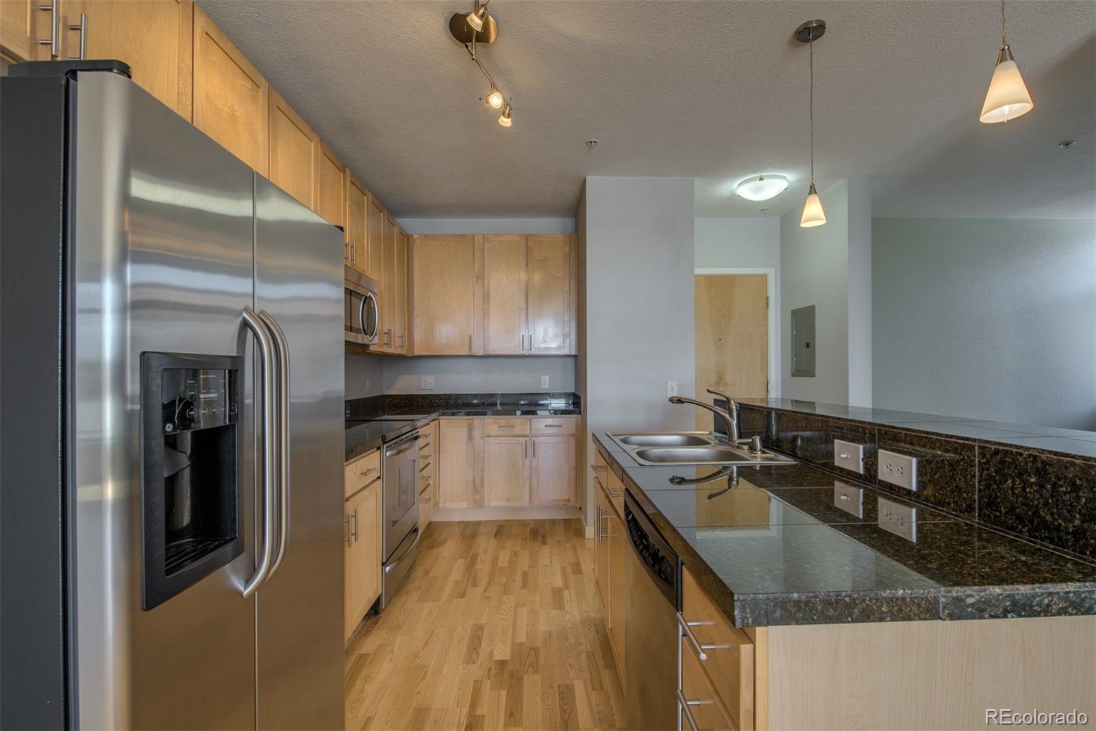 3101 Blake Street, Unit 308 Denver, CO 80205 - Photo 6 of 30 a kitchen with granite countertop a sink a counter top space stainless steel appliances and cabinets
