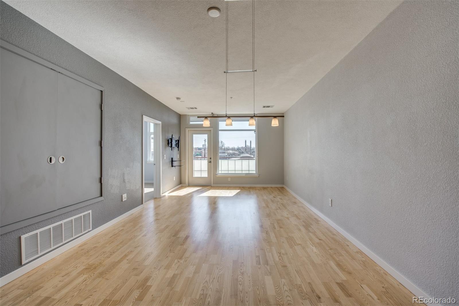 3101 Blake Street, Unit 308 Denver, CO 80205 - Photo 7 of 30 a view of an empty room with wooden floor and a window