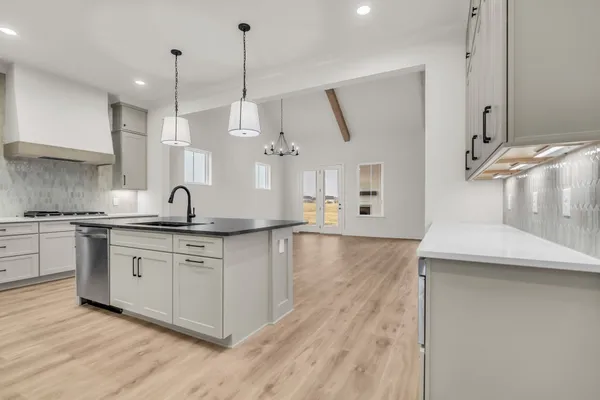 a kitchen with stainless steel appliances granite countertop a sink a stove a refrigerator and white cabinets with wooden floor