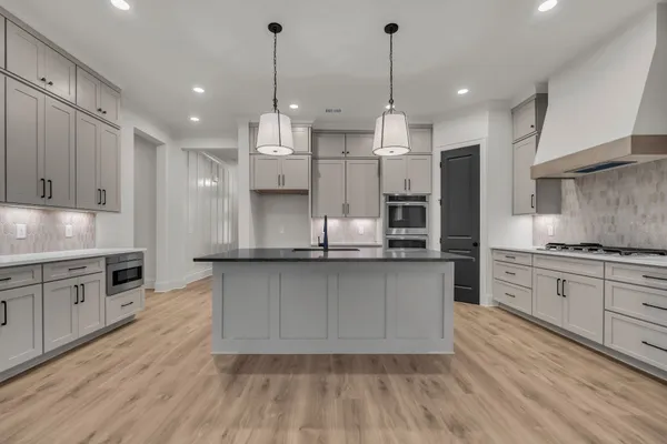 a large kitchen with granite countertop a large counter top a sink stainless steel appliances and cabinets