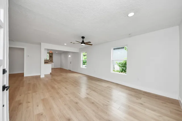 an empty room with wooden floor and windows