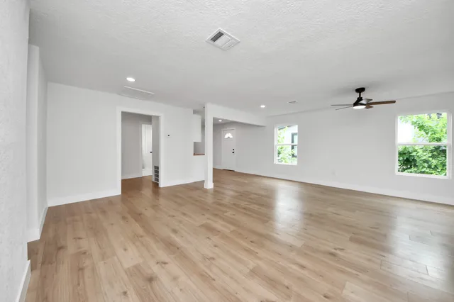 an empty room with wooden floor and natural light