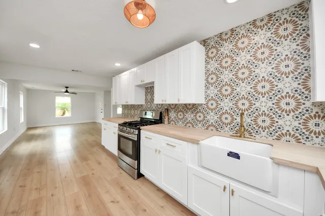 a kitchen with stainless steel appliances granite countertop a stove a sink and white cabinets with wooden floor