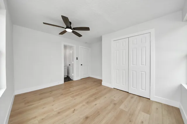 a view of empty room with wooden floor and ceiling fan