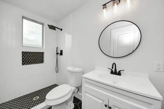 a bathroom with a sink a mirror a toilet and a shower