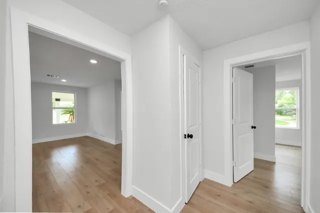 an empty room with wooden floor and windows