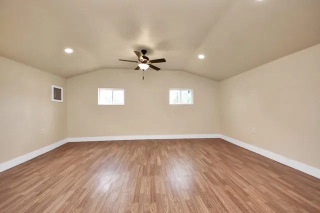 a view of an empty room with a window and wooden floor