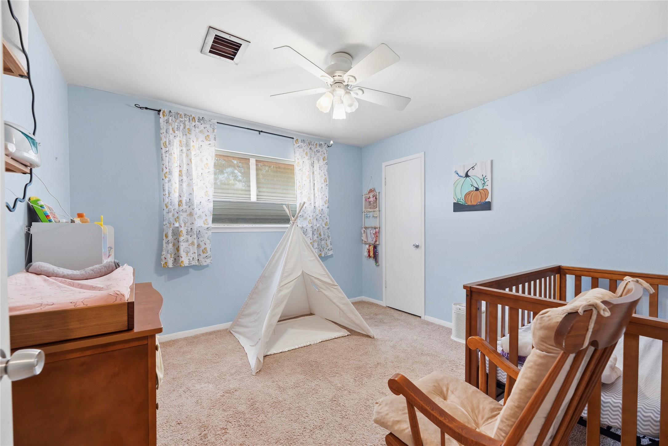 14203 Wickersham Lane Houston, TX 77077 - Photo 15 of 25 Bright and airy secondary bedroom featuring soft neutral flooring, light wall tones, a large window for natural lighting, a built-in closet, and a multi-blade ceiling fan. Cell shades allow you to lower or raise for the ideal lighting.