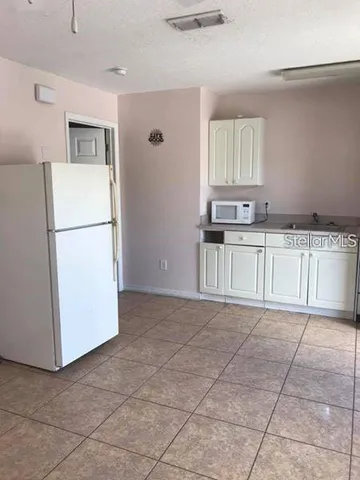 a kitchen with granite countertop a refrigerator and a stove top oven
