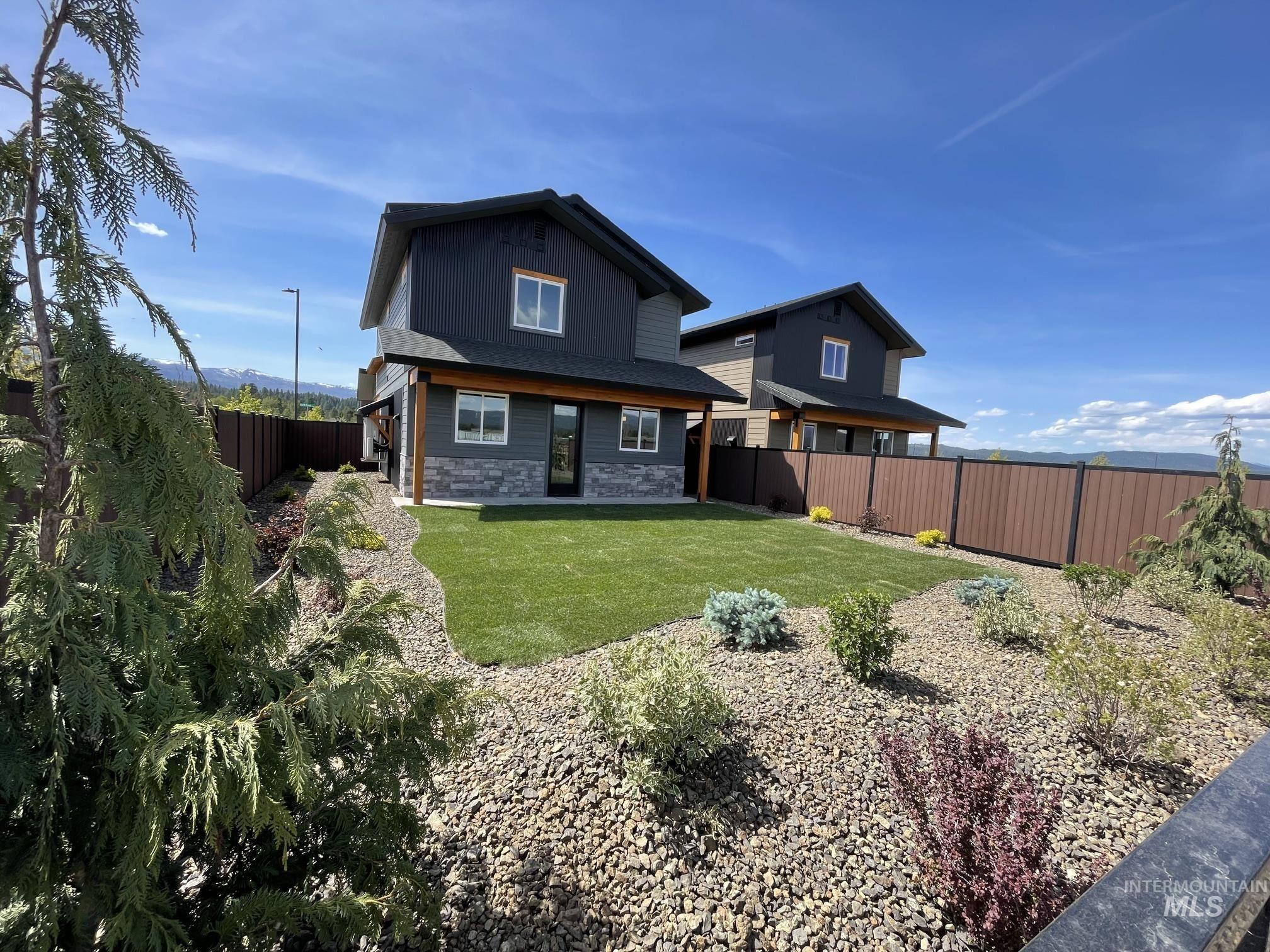 10 North Crk Way Cascade, ID 83611 - Photo 20 of 25 Rear exterior featuring dark gray siding, stone accents, a covered patio, and a manicured lawn