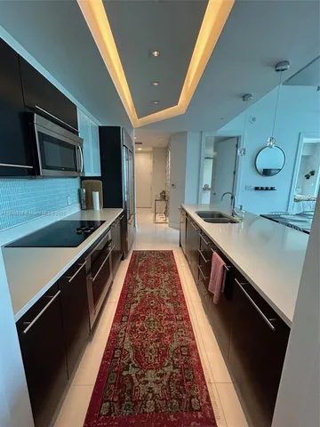 a large kitchen with stainless steel appliances a large counter top a stove a sink and a refrigerator