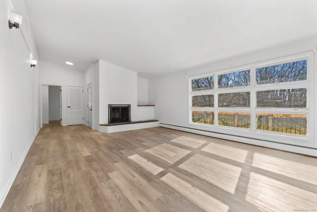 a view of an empty room with a window and a kitchen