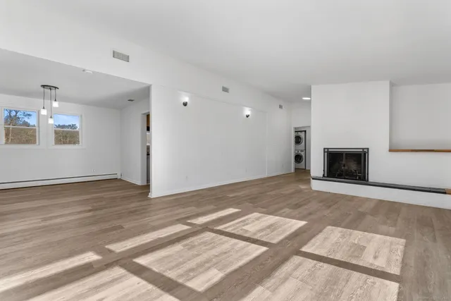 a view of an empty room with wooden floor and a fireplace