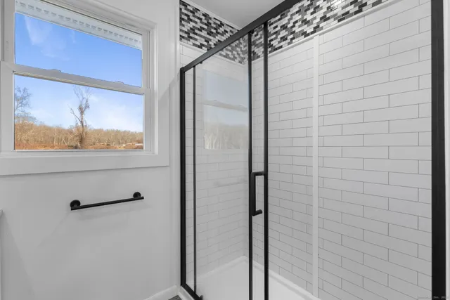 a bathroom with a glass shower door and a window