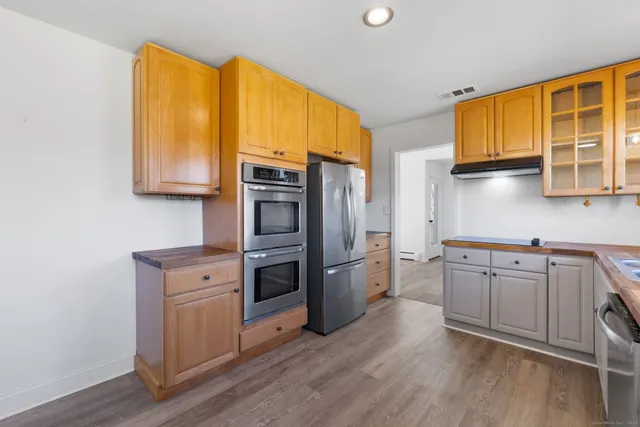 a kitchen with stainless steel appliances granite countertop a refrigerator a stove and a wooden cabinets