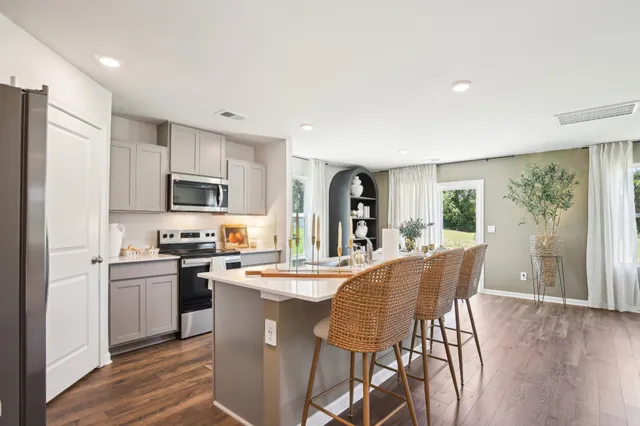 a living room with furniture a clock and a view of kitchen