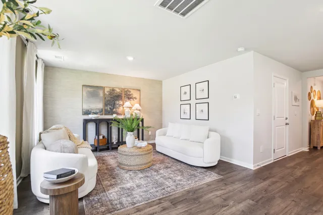 a living room with furniture potted plant and kitchen view
