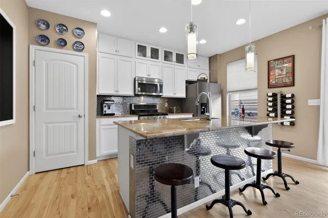 a kitchen with stainless steel appliances granite countertop a stove top oven a sink a dining table and chairs