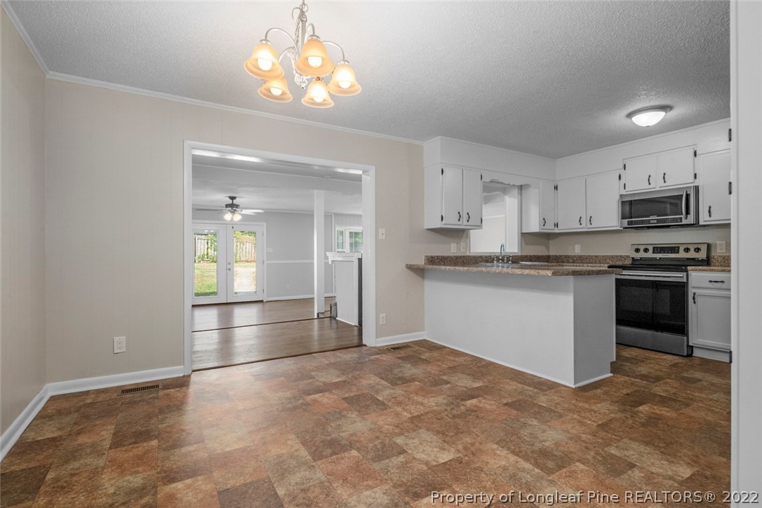 6614 Wake Forest Road Fayetteville, NC 28311 - Photo 13 of 48 a kitchen with granite countertop a refrigerator and a stove top oven