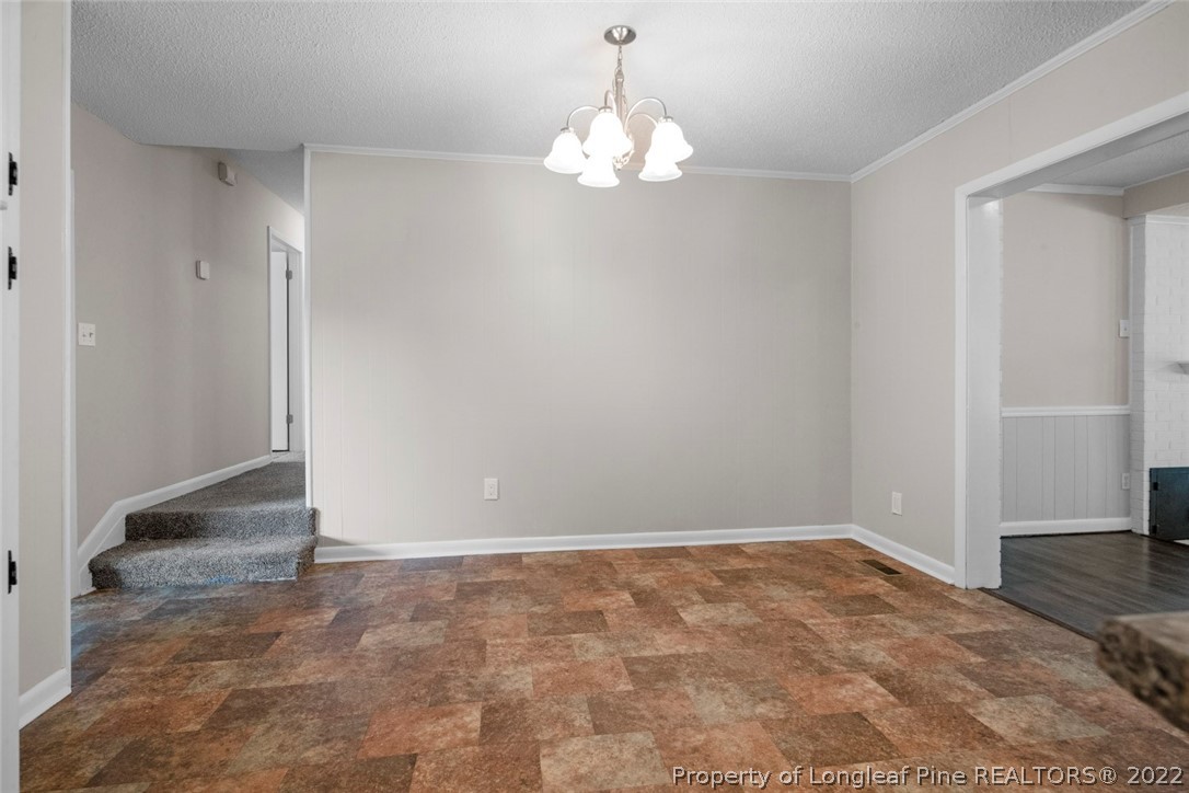6614 Wake Forest Road Fayetteville, NC 28311 - Photo 14 of 48 an empty room with a chandelier fan and kitchen view