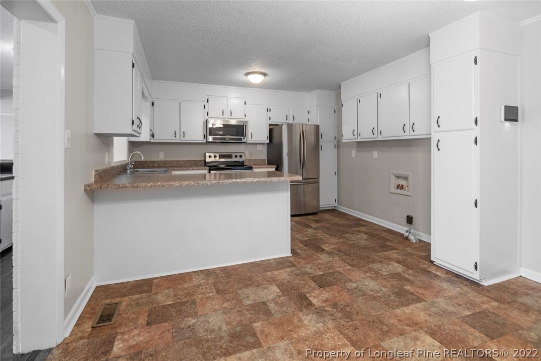 6614 Wake Forest Road Fayetteville, NC 28311 - Photo 16 of 48 a kitchen with stainless steel appliances a refrigerator sink and white cabinets