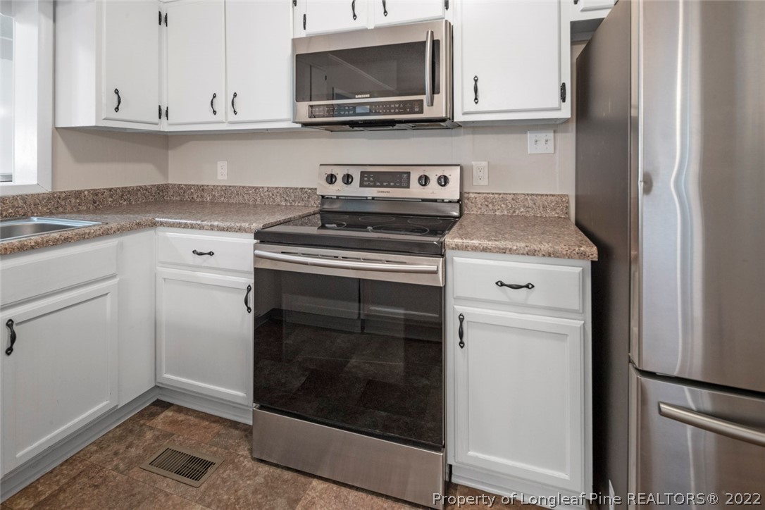 6614 Wake Forest Road Fayetteville, NC 28311 - Photo 19 of 48 a kitchen with granite countertop white cabinets stainless steel appliances and sink