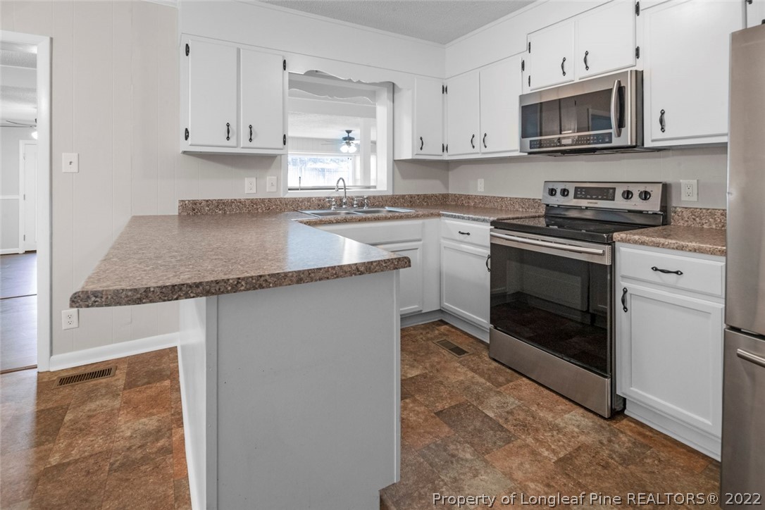 6614 Wake Forest Road Fayetteville, NC 28311 - Photo 21 of 48 a kitchen with stainless steel appliances granite countertop a stove a sink and a microwave