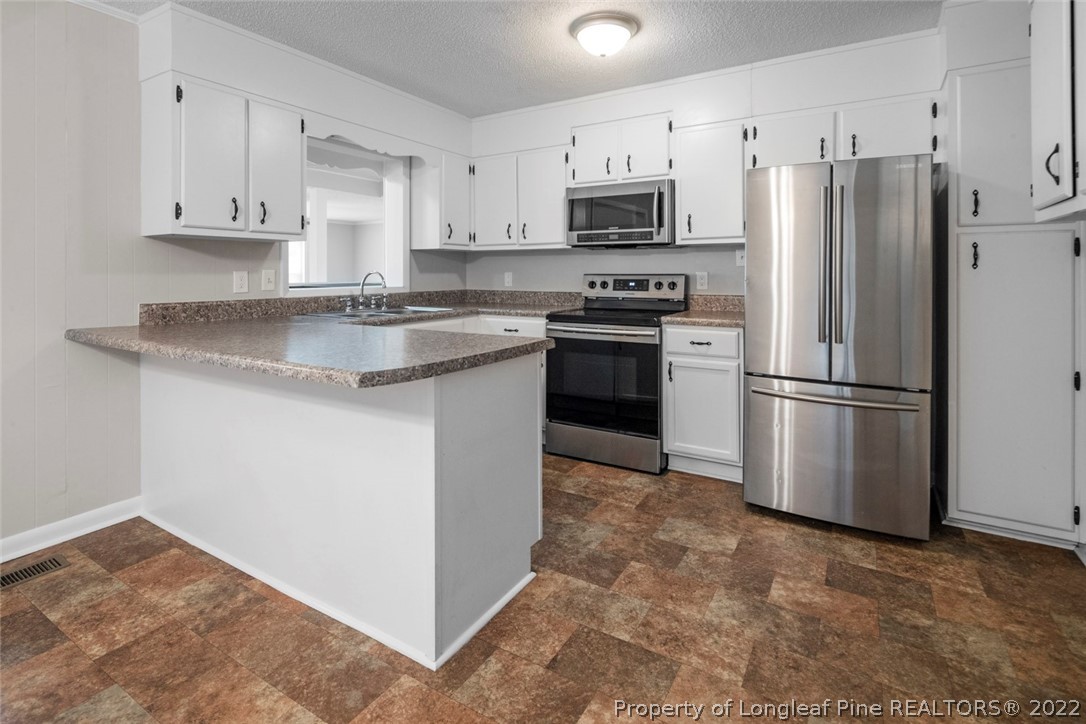 6614 Wake Forest Road Fayetteville, NC 28311 - Photo 23 of 48 a kitchen with stainless steel appliances granite countertop a refrigerator stove a sink and a microwave