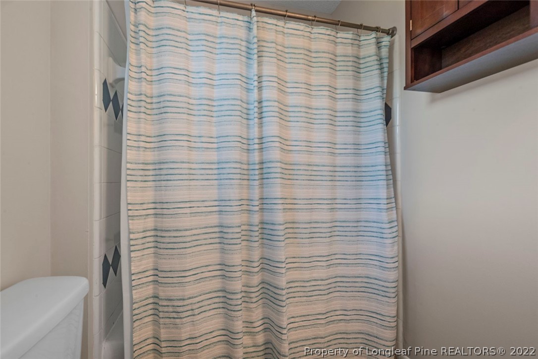 6614 Wake Forest Road Fayetteville, NC 28311 - Photo 42 of 48 a bathroom with a shower curtain and a toilet