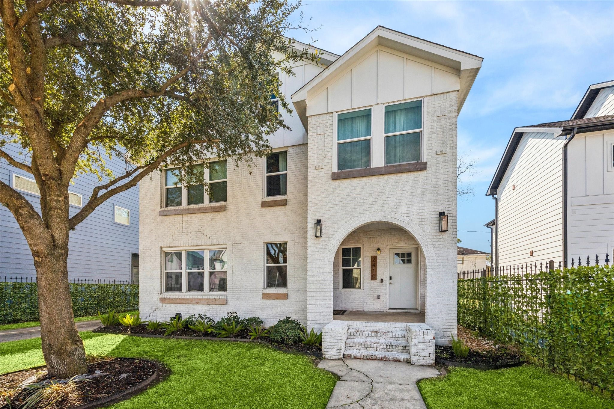 2410 Truxillo Street Houston, TX 77004 - Photo 2 of 41 Inviting front elevation showcasing arched covered entry, fresh exterior paint, and manicured lawn framed by wrought iron fencing for a timeless presentation.