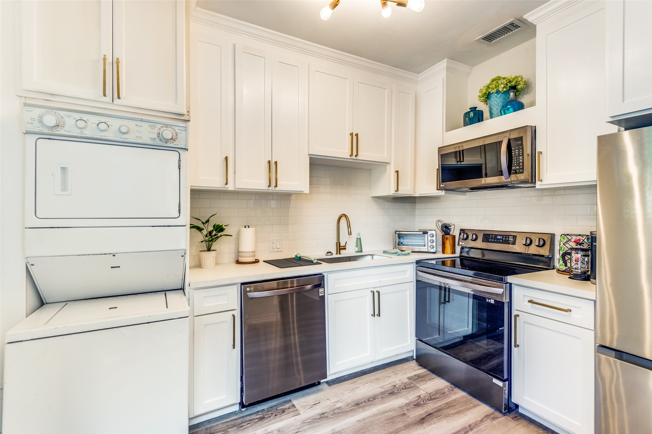 2410 Truxillo Street Houston, TX 77004 - Photo 27 of 41 Unit C (Studio): Bright, updated kitchen featuring shaker-style cabinetry, quartz countertops, subway tile backsplash, and stainless steel appliances. Elegant gold hardware and modern lighting create a clean, contemporary feel.