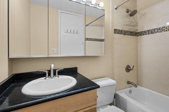 a bathroom with a granite countertop sink a toilet and bathtub