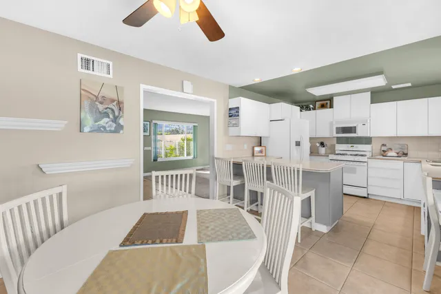 a kitchen with white cabinets and chairs
